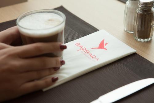a woman holding a glass of coffee on a table at Barbara Piran Beach Hotel in Piran