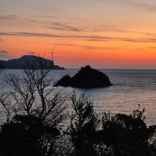 an island in the ocean with a sunset at 대마도쇼핑구마에하우스 in Tsushima