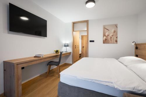 a bedroom with a bed and a desk with a television at Wellness Hotel Repiska in Demanovska Dolina
