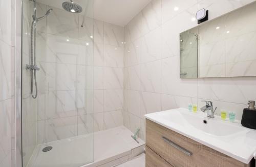 une salle de bain blanche avec une douche et un lavabo dans l'établissement Mobility lease - Studio 10 minutes from Paris, à Boulogne-Billancourt