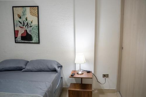 a bedroom with a bed and a table with a lamp at ALQUILO''APARTAMENTO COMPLETO con ZONA PRIVADA SOCIAL BARBECUE BBQ'' para FAMILIAS-3 HABITACION-2 duchas in Cali