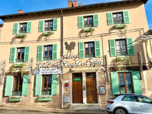 a building with green shutters and a car parked in front at Hôtel Au Coq Dort Spa in Châtillon-sur-Chalaronne