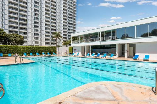a large swimming pool with blue chairs and a building at The violet-Santa Monica highrise beach front&view in Los Angeles