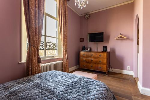 a bedroom with a bed and a dresser and a window at Landgoed Loenen B&B in Slijk-Ewijk