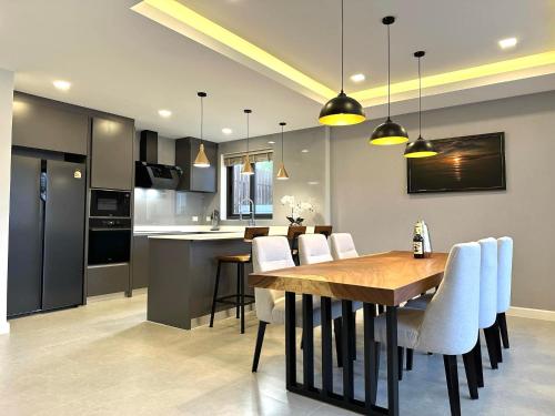 a kitchen and dining room with a wooden table and chairs at Zensiri Luxury 3BDR Pool Villa in Pattaya
