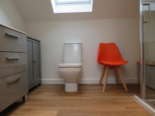 a orange chair in a room with a toilet at The Loft at Log Ness in Inverness