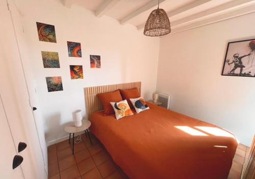 - une chambre dotée d'un lit avec des draps orange et des photos murales dans l'établissement CHAMPIONNET - City center - Quiet, à Auch