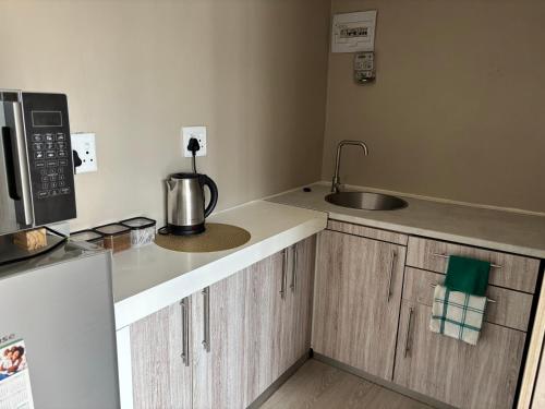 a small kitchen with a sink and a microwave at Bachelor Flat B in Cape Town