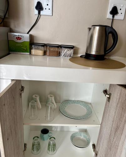 a kitchen shelf with dishes and a kettle on it at Bachelor Flat B in Cape Town