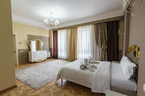 a bedroom with a white bed and a chandelier at Park Hotel al Bustan in Shymkent