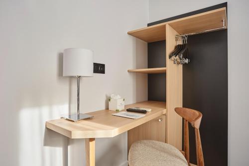 a desk in a room with a lamp and a chair at Hotel Gabriel Issy Paris in Issy-les-Moulineaux