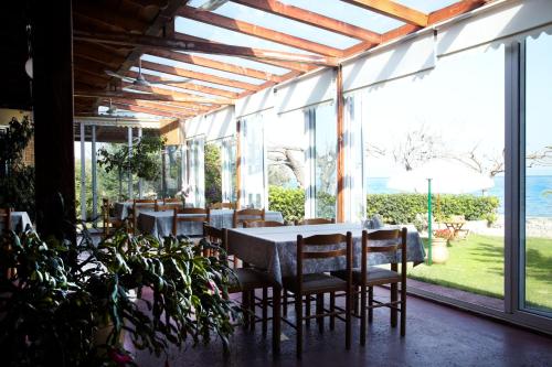 a dining room with a table and chairs and windows at Evoikos beach & resort in Livanátai