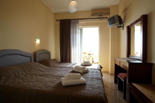 a bedroom with two towels on a bed with a window at Evoikos beach & resort in Livanátai