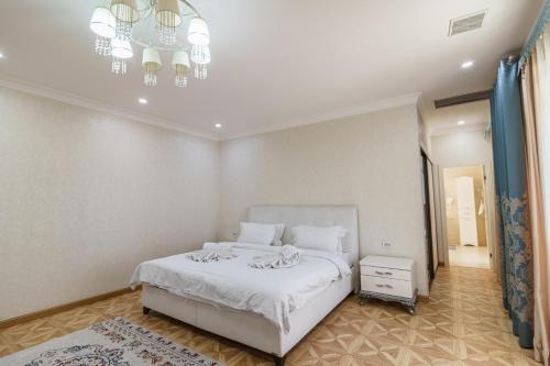 a bedroom with a white bed and a chandelier at Park Hotel al Bustan in Shymkent