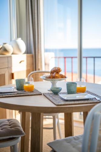 une table avec une assiette de nourriture et deux verres de jus d'orange dans l'établissement Le Duplex de la Mer, vue magnifique, accès plage, à Fréjus