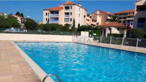 une grande piscine bleue en face de certains bâtiments dans l'établissement L'Auriasque - A 5 min à pied du centre-ville, à Fréjus