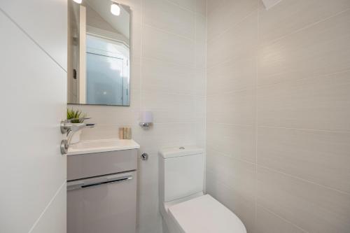 a white bathroom with a toilet and a sink at Villa PAM, ALYA Beach House with pool and Hot Tub in Alcudia