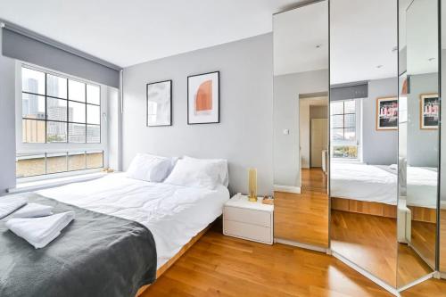 a bedroom with a large white bed and a mirror at Canary Wharf Views in London