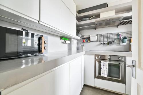 a kitchen with white cabinets and a microwave at Canary Wharf Views in London