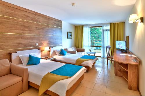 a hotel room with two beds and a couch at Les Magnolias Hotel in Primorsko