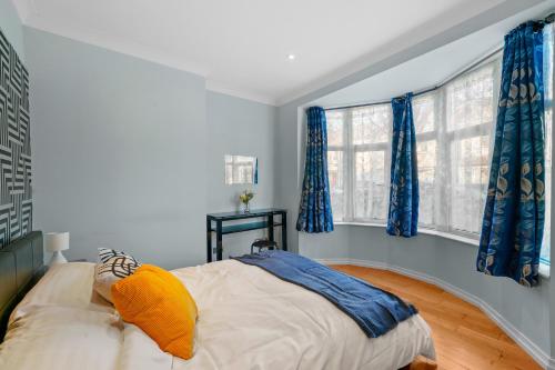 a bedroom with a large bed with blue curtains at Sunny Side Apartment Wembley in Harrow on the Hill
