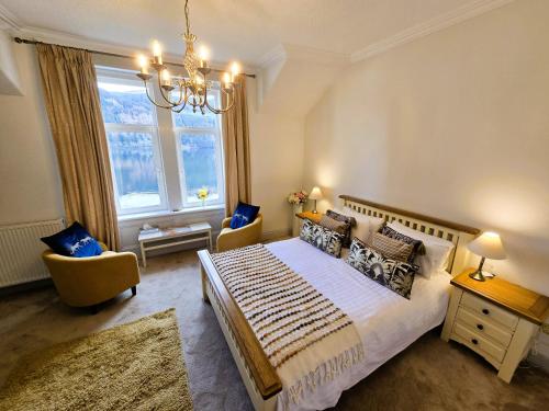 a bedroom with a bed and two chairs and a window at Lochwood Guest House in Lochgoilhead