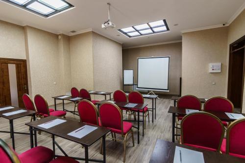 a classroom with tables and red chairs and a screen at Park Hotel al Bustan in Shymkent