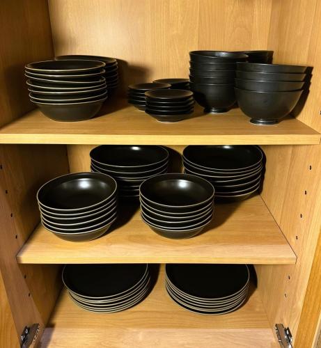 a wooden cabinet filled with black bowls and plates at P's Wood 伊豆高原 in Ito