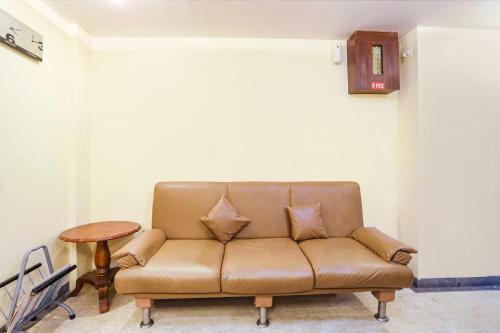 a brown couch in a living room with a table at FabHotel Shubhangan - Nr Bandra in Mumbai