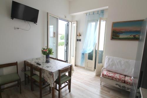 a living room with a table and chairs and a television at Perla in Marina di Mancaversa