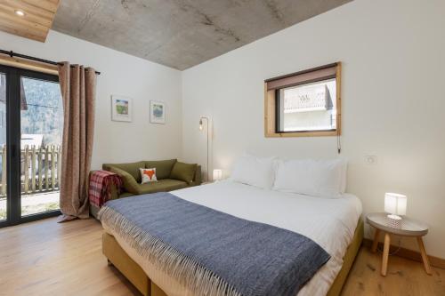a bedroom with a bed and a couch and a window at Chalet C, near Morzine in Le Biot