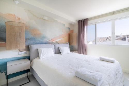 a bedroom with a white bed with a painting on the wall at Casa Lola in Sitio de Calahonda