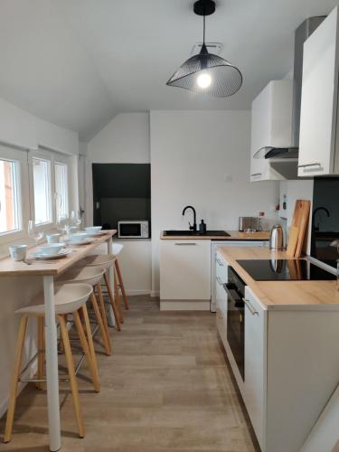 une cuisine avec des armoires blanches et une table et des chaises dans l'établissement Maison Rénovée & Spacieuse, Idéale Familles & Groupes, Proche Aéroport, à Beauvais