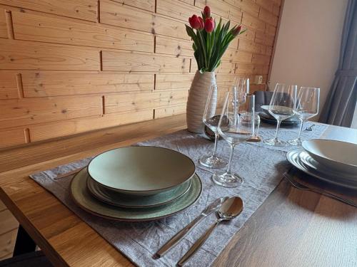 a table with plates and glasses and a vase with flowers at moderne Apartments am Attersee Dachsteinblick - ruhige Lage mit traumhaften Blick in Nussdorf am Attersee