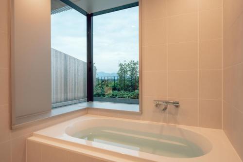 a bath tub with a large window in a bathroom at Hotel Vison in Taki
