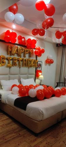 a bed with a happy birthday sign and red and white balloons at Aar Kay Inn & Suites in Jalandhar