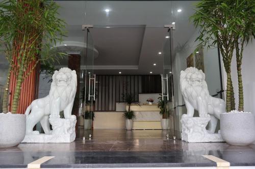 two white statues of lions in a lobby at The Grand Diamond C Hotel in Trung Ðồng