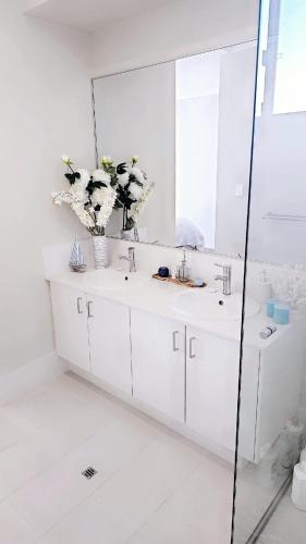 a white bathroom with two sinks and a mirror at Eglinton Elegance - Hamptons Retreat in Yanchep