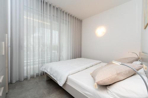 a white bedroom with a bed and a window at IseoLakeRental - Casa Marcellino in Clusane sul Lago