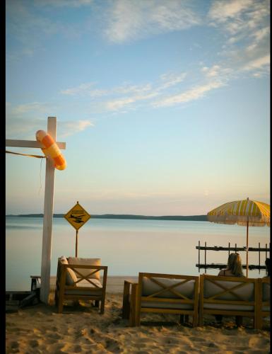 a cross on the beach with two beds and an umbrella at Hôtel Latécoère in Biscarrosse