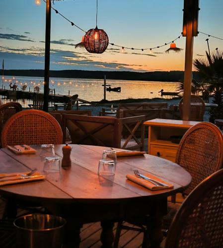 a wooden table in a restaurant with a view of the water at Hôtel Latécoère in Biscarrosse