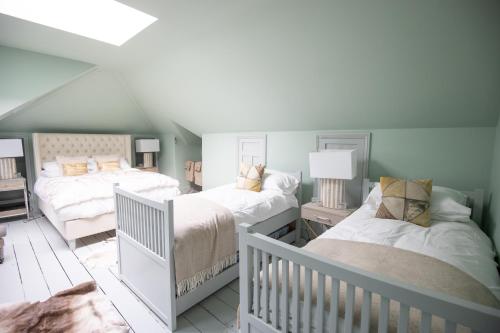 a attic bedroom with two beds and a crib at Vale House, Belvoir Castle in Grantham