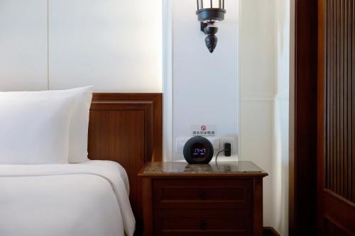 a bedroom with a bed and a clock on a night stand at InterContinental Xishuangbanna Resort by IHG in Jinghong