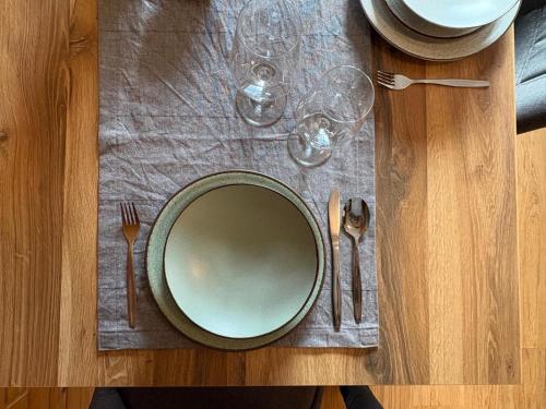 a wooden table with a plate and fork and knife at moderne Apartments am Attersee Dachsteinblick - ruhige Lage mit traumhaften Blick in Nussdorf am Attersee