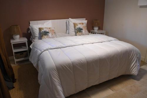 une chambre avec un grand lit blanc avec deux tables de nuit dans l'établissement Appartement au Domaine 