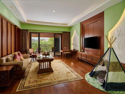 a living room with a couch and a tv at InterContinental Xishuangbanna Resort by IHG in Jinghong