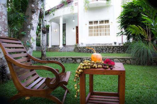 a table with a bowl of fruit next to a chair at KumbukVilla in Hanwella