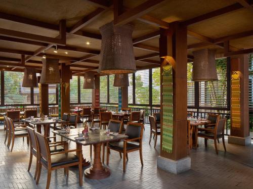 a restaurant with wooden tables and chairs and windows at InterContinental Xishuangbanna Resort by IHG in Jinghong