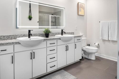 a white bathroom with two sinks and a toilet at Modern Uptown 2BR Free Parking & Private Balcony in Charlotte