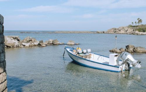 a small blue boat sitting in the water at Caesarea Vacation Rooms in Caesarea